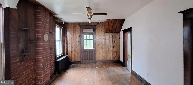 a view of a hallway with wooden floor and a ceiling fan