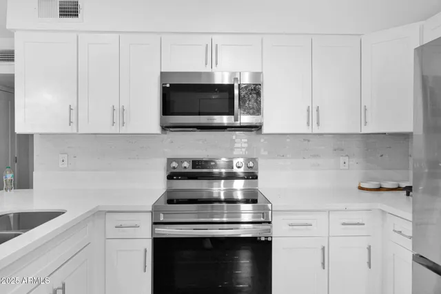 a kitchen with white cabinets and black appliances