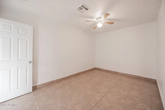 an empty room with a chandelier fan and closet area
