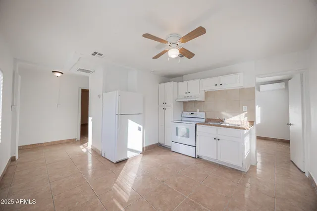 a large white kitchen with a stove a sink dishwasher and a refrigerator with white cabinets