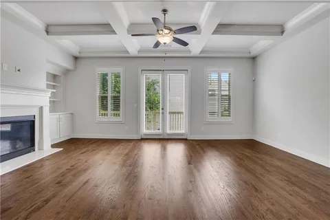 a view of an empty room with wooden floor fireplace and a window