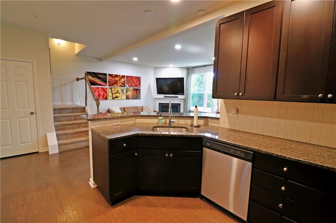 4502 Benjamin Court Emmaus, PA 18049 - Photo 11 of 53 A well-appointed kitchen features dark wood cabinetry and granite countertops, opening to a spacious living area.