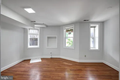an empty room with wooden floor and windows
