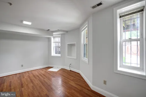 a view of empty room with wooden floor and fan