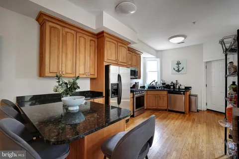 a large kitchen with stainless steel appliances kitchen island granite countertop a refrigerator a stove a sink dishwasher and a dining table with wooden floor