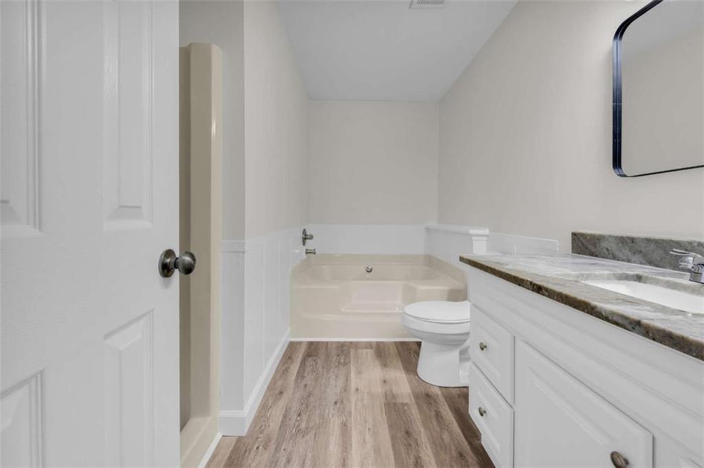 253 Sanders Old Farm Road Crawford, GA 30630 - Photo 28 of 34 a bathroom with a granite countertop toilet a sink and wooden floor