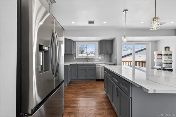 a open kitchen with stainless steel appliances granite countertop a refrigerator a sink and a stove with wooden floor