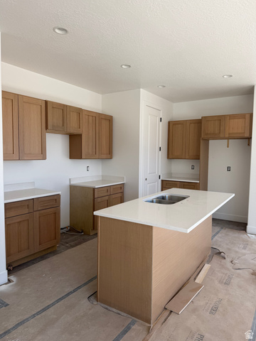 4956 North 925 East, Unit 87 Enoch, UT 84721 - Photo 3 of 12 Kitchen featuring a center island with sink, wood finish cabinets, light stone counters, and recessed lighting