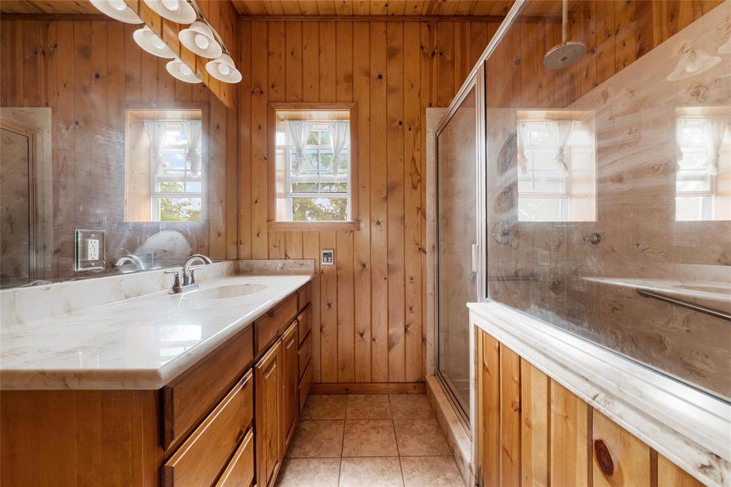 237 Lcr 711 Kosse, TX 76653 - Photo 19 of 40 Full bath with tile patterned flooring, vanity, wooden walls, and a stall shower