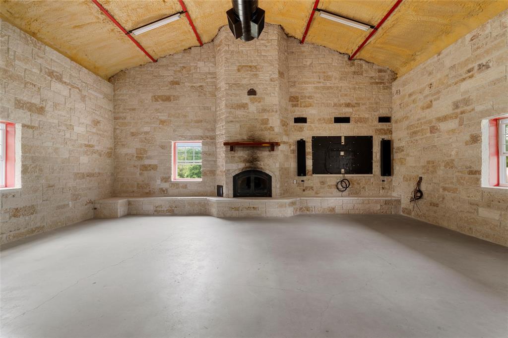 237 Lcr 711 Kosse, TX 76653 - Photo 23 of 40 Unfurnished living room with concrete flooring, lofted ceiling, and a fireplace