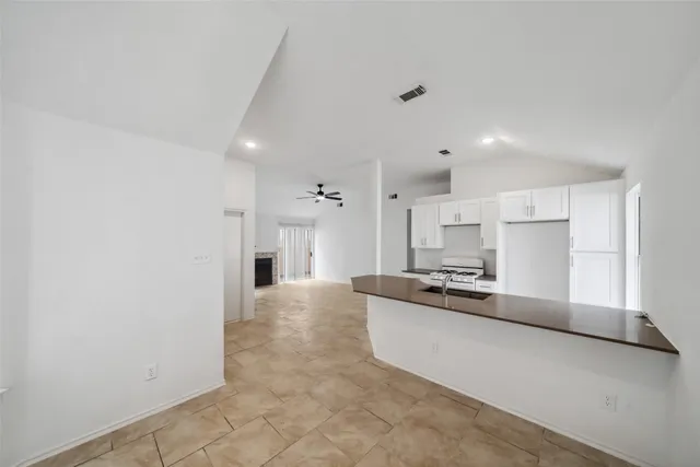 a large kitchen with granite countertop a stove a sink dishwasher and a refrigerator with wooden floor