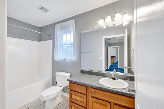 a bathroom with a granite countertop sink a toilet and a mirror
