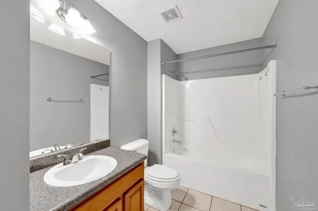 a bathroom with a granite countertop sink toilet mirror vanity and shower