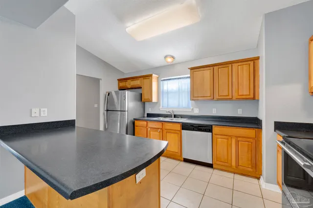 a kitchen with stainless steel appliances granite countertop a sink a stove counter space and cabinets