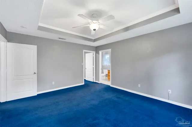 a view of an empty room with chandelier fan and wooden floor