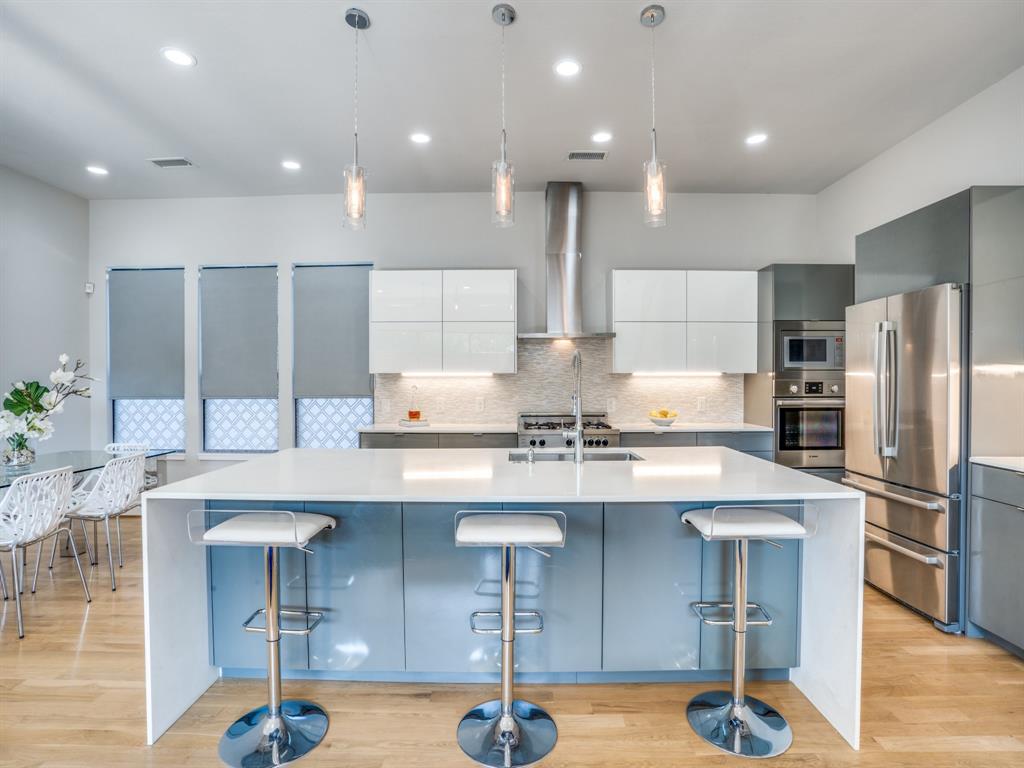 a kitchen with stainless steel appliances kitchen island a table chairs refrigerator and sink