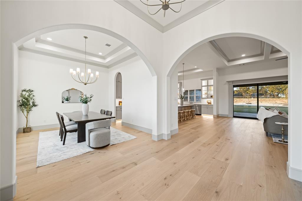 724 Cooper Trail Weatherford, TX 76087 - Photo 13 of 37 Expansive wood-finish flooring throughout, featuring a dining area with a tray ceiling and chandelier lighting