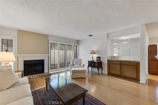 a living room with furniture a fireplace a flat screen tv and kitchen view