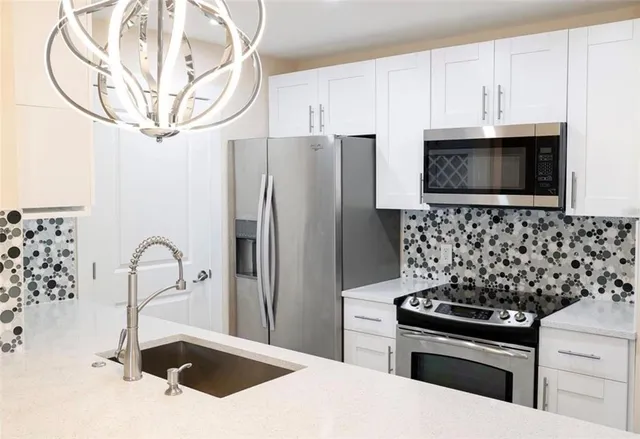 a kitchen with stainless steel appliances granite countertop a sink a stove a microwave and refrigerator