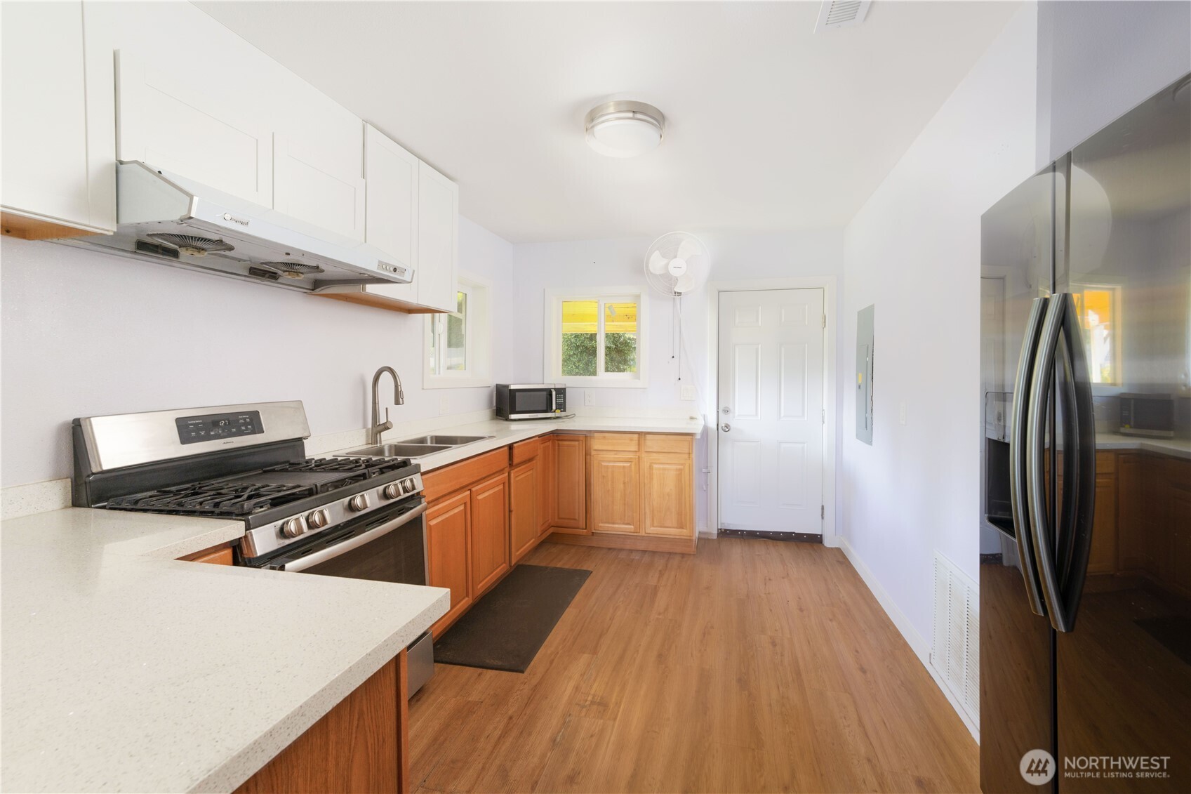 5104 Northwest Sammamish Road Issaquah, WA 98027 - Photo 14 of 24 a kitchen with stainless steel appliances a refrigerator a sink dishwasher a stove and white cabinets with wooden floor