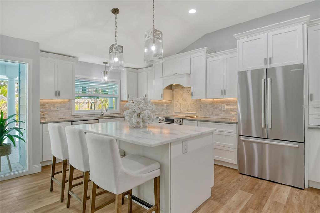 4852 Featherbed Lane Sarasota, FL 34242 - Photo 22 of 79 a kitchen with stainless steel appliances granite countertop a refrigerator a sink dishwasher a dining table and chairs with wooden floor