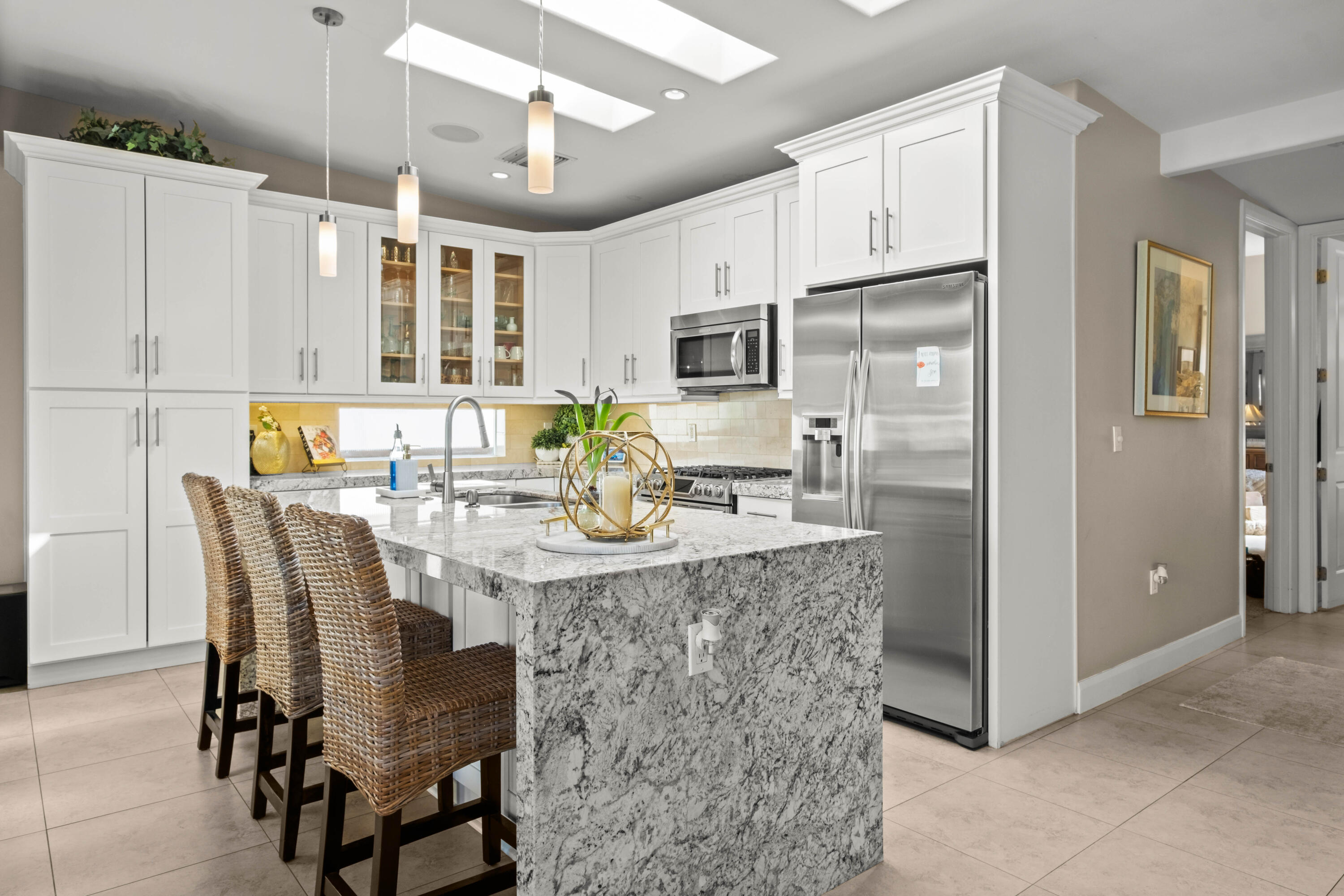 a kitchen with stainless steel appliances granite countertop a dining table chairs refrigerator and cabinets