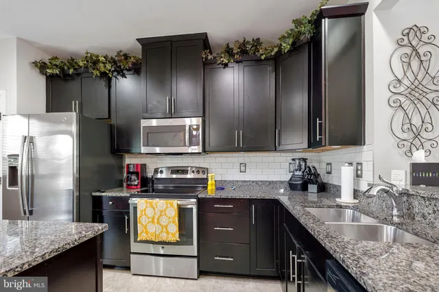 a kitchen with granite countertop a refrigerator and a sink