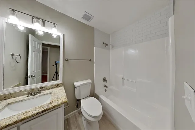 a bathroom with a granite countertop toilet a sink and a mirror