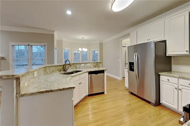 a large kitchen with stainless steel appliances granite countertop a sink a stove a refrigerator a washer and dryer with wooden floor