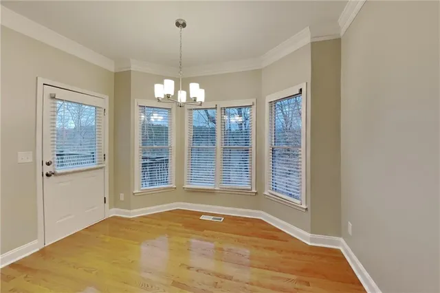 a view of an empty room with a chandelier fan and wooden floor