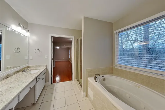 a spacious bathroom with a granite countertop tub sink and mirror