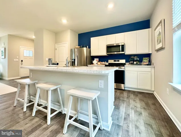 a kitchen with stainless steel appliances granite countertop a table chairs refrigerator and microwave