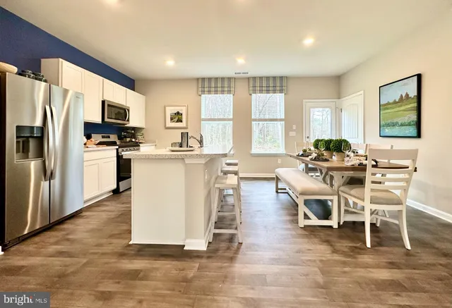 a dining room with kitchen island granite countertop a refrigerator and a stove top oven