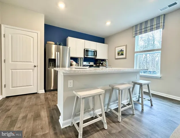 a kitchen with stainless steel appliances a dining table chairs refrigerator and sink