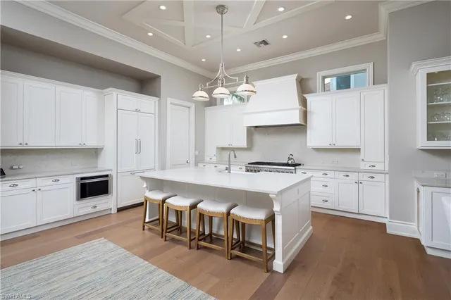 a large white kitchen with cabinets a sink and stainless steel appliances