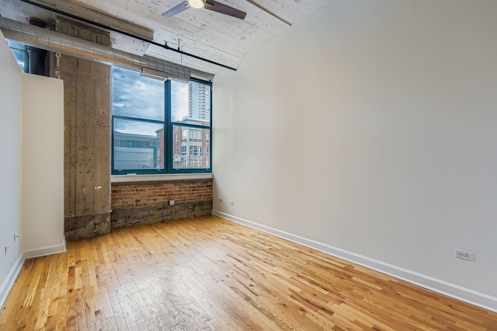 221 East Cullerton Street, Unit 317 Chicago, IL 60616 - Photo 11 of 16 an empty room with wooden floor and windows