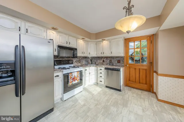a kitchen with granite countertop a stove a sink and white cabinets with wooden floor