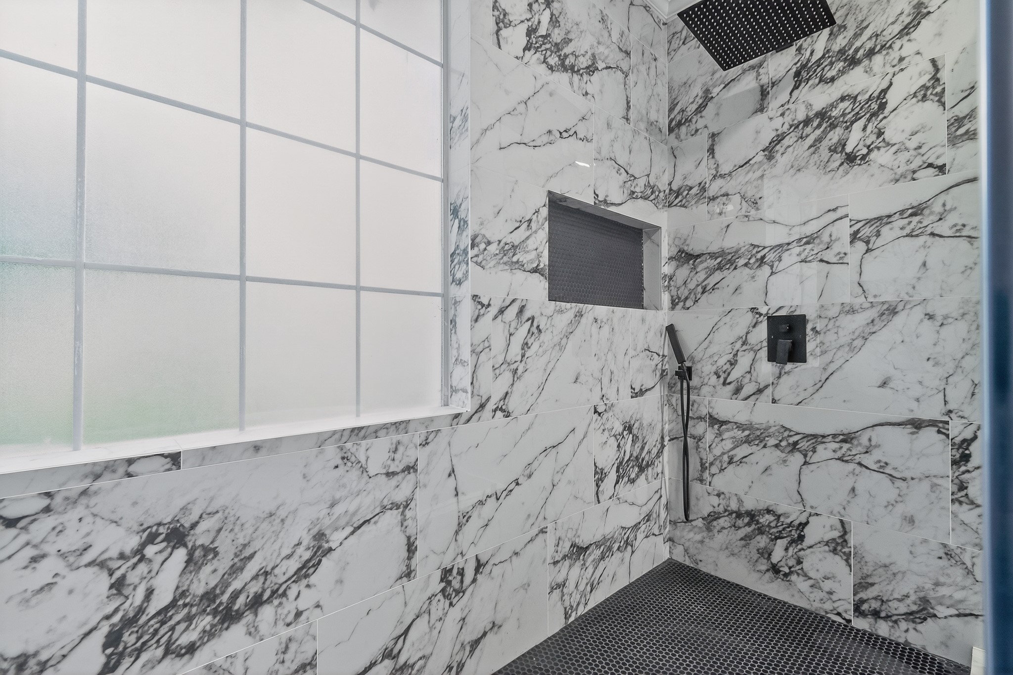 523 Rampart Lane Conroe, TX 77302 - Photo 17 of 41 Experience resort-style luxury in this stunning walk-in shower with floor to ceiling marble look tile, rainfall shower system, frameless glass, and designer black fixtures.