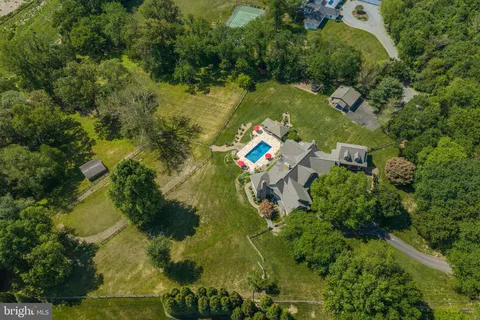 an aerial view of a residential houses with outdoor space and trees all around