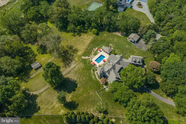 an aerial view of a residential houses with outdoor space and trees all around