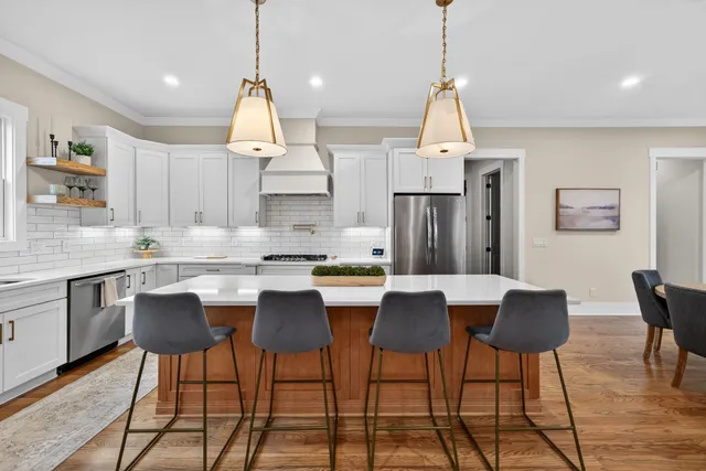 a kitchen with stainless steel appliances white cabinets a sink a stove a refrigerator and island