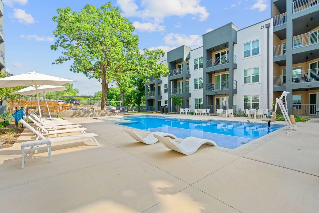 4901 Springdale Road, Unit 2308 Austin, TX 78723 - Photo 4 of 19 An inviting outdoor pool with comfortable lounge seating offers relaxation alongside a contemporary residential building.