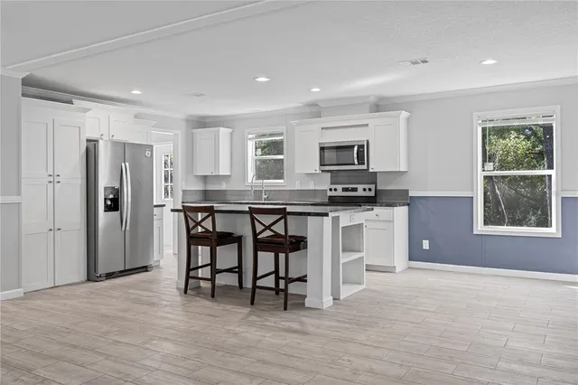 a kitchen with granite countertop a stove a microwave a sink and a refrigerator