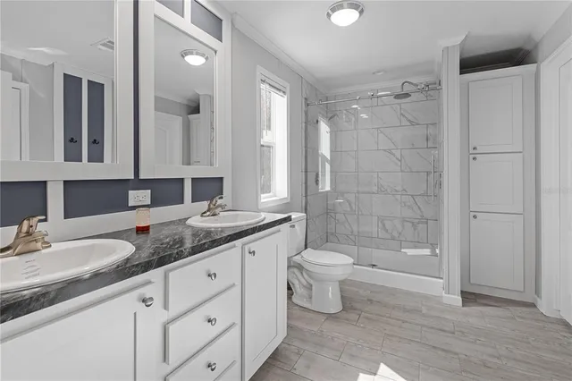 a bathroom with a granite countertop sink a toilet and shower