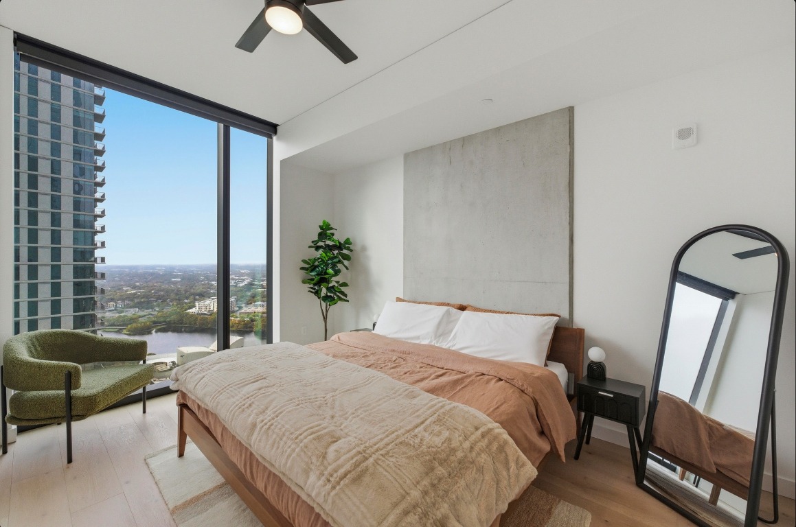 610 Davis Street, Unit 3104 Austin, TX 78701 - Photo 12 of 40 Bedroom featuring a wall of windows, wood finished floors, and a ceiling fan