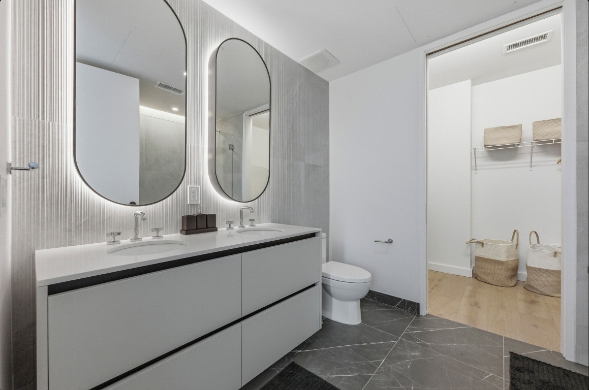 610 Davis Street, Unit 3104 Austin, TX 78701 - Photo 13 of 40 Bathroom with a walk in closet, double vanity, and dark marble finish floors