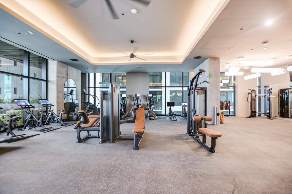 610 Davis Street, Unit 3104 Austin, TX 78701 - Photo 34 of 40 Workout area featuring a ceiling fan, a tray ceiling, a wall of windows, and carpet