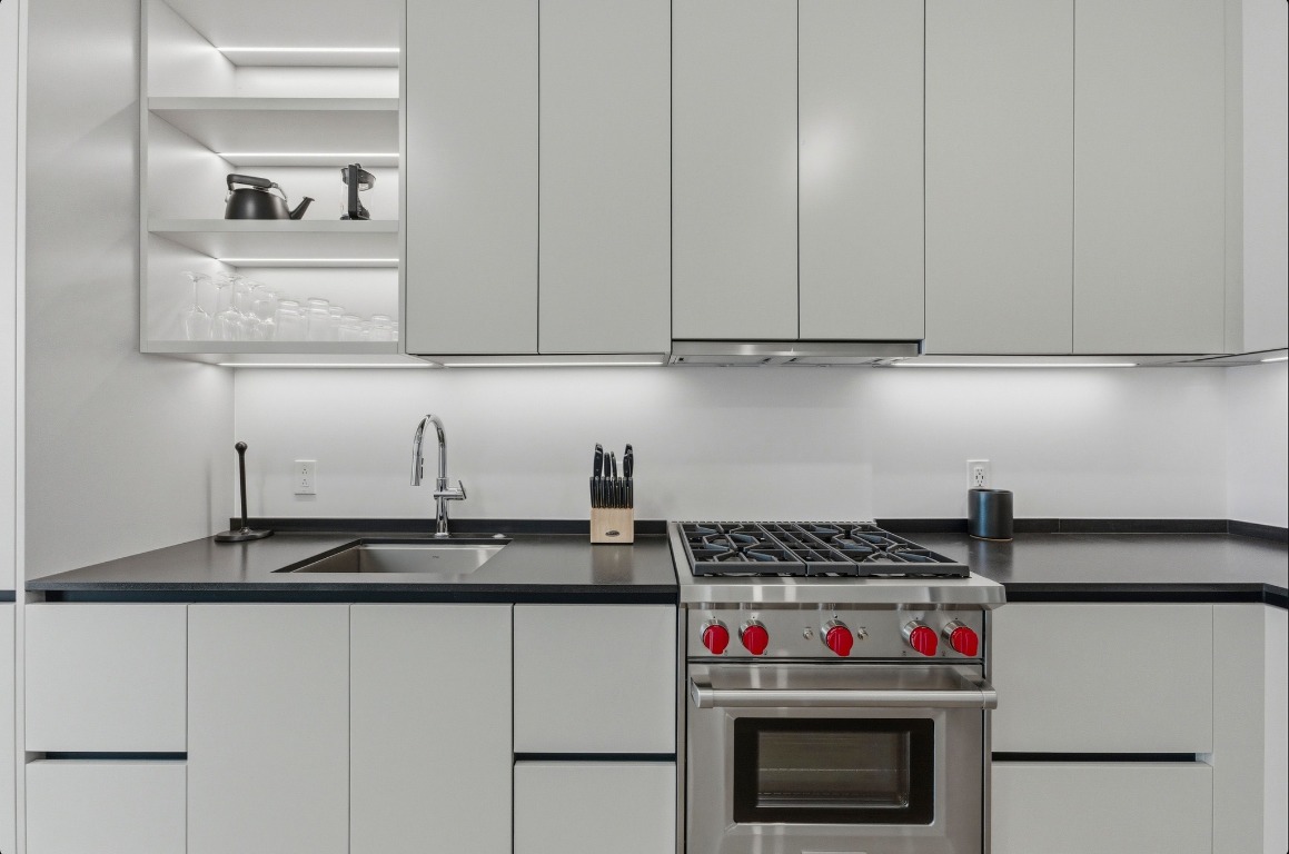 610 Davis Street, Unit 3104 Austin, TX 78701 - Photo 6 of 40 Kitchen featuring luxury stove, dark countertops, modern cabinets, open shelves, and under cabinet range hood