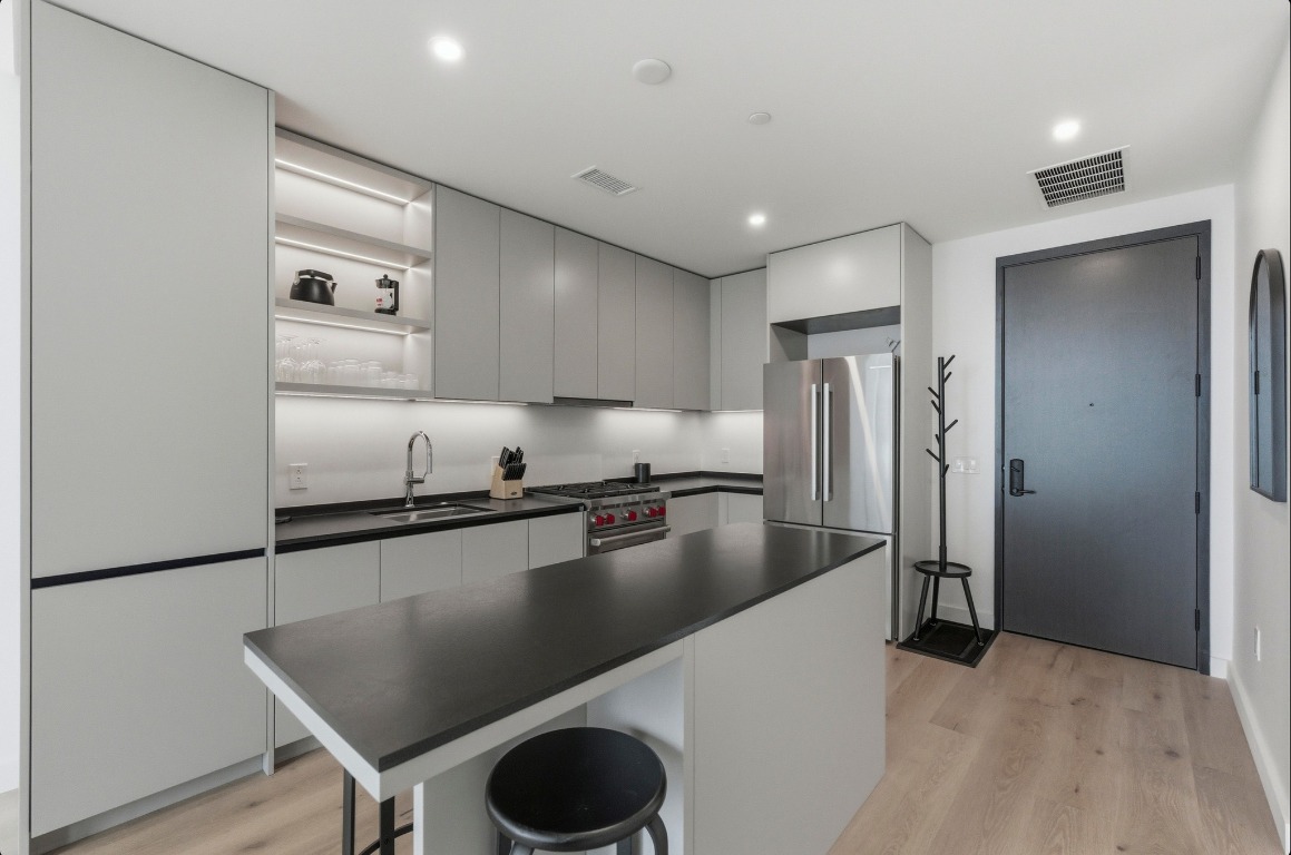 610 Davis Street, Unit 3104 Austin, TX 78701 - Photo 10 of 40 Kitchen with modern cabinets, open shelves, a breakfast bar area, dark countertops, and stainless steel appliances