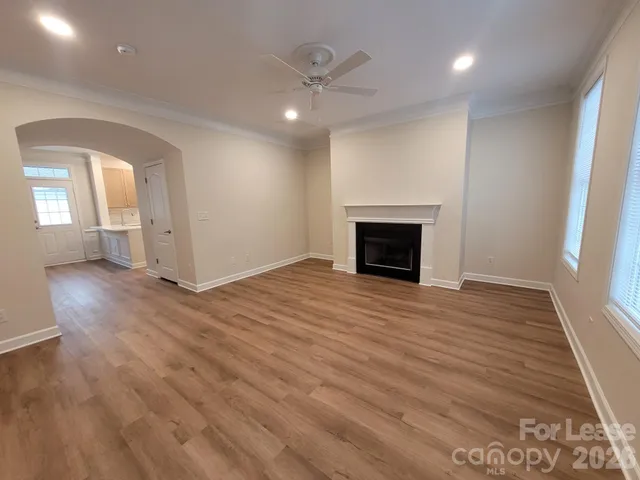 an empty room with wooden floor fireplace and windows
